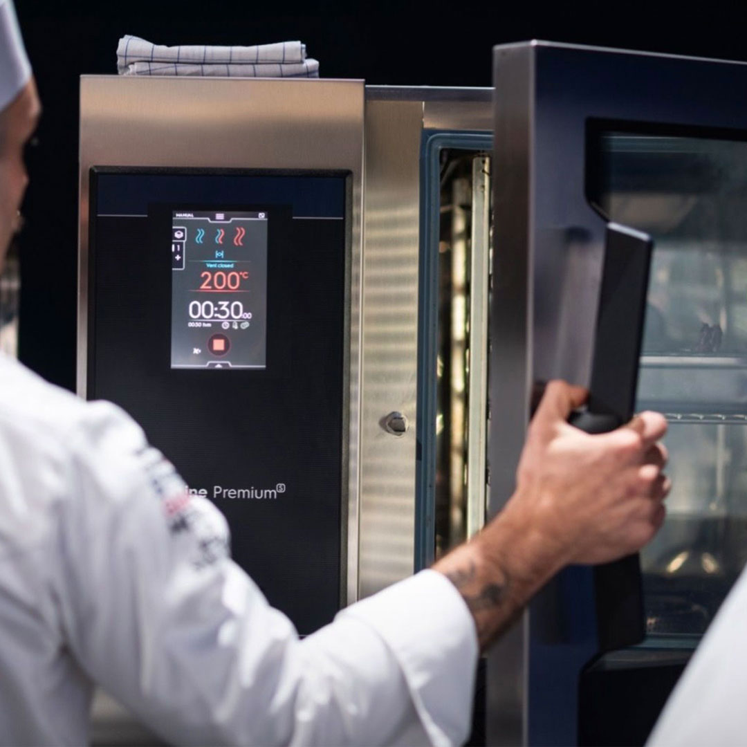 Chef using combi oven in a busy commercial kitchen